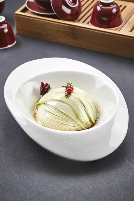 白色椭圆瓷盘装的凉拌浇汁西芹丝图片