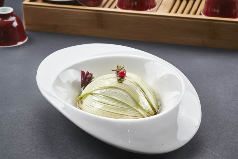 白色椭圆瓷盘装的凉拌浇汁西芹丝图片