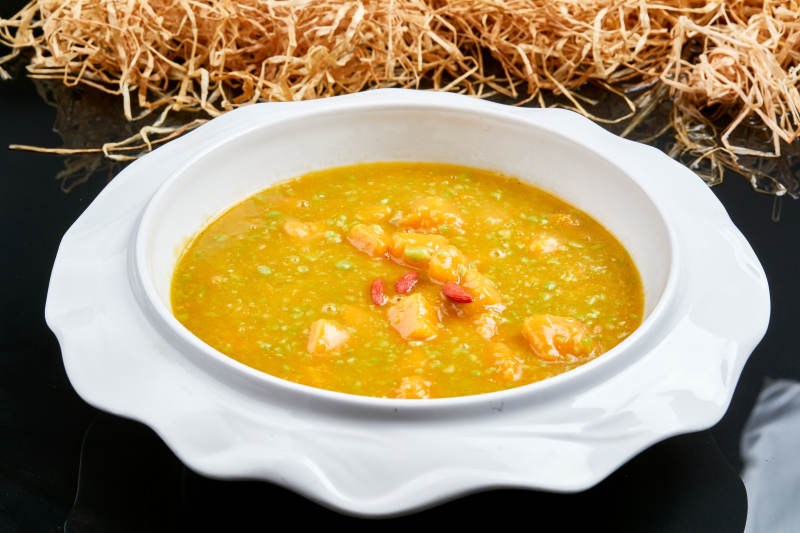 白色瓷餐具装的浓香青豆金米南瓜羹图片