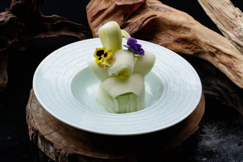 青瓷盘装的蘸汁西芹丝摆放在樟木砧板上图片