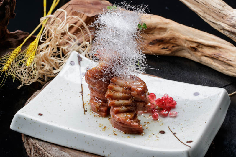 青瓷盘装的糖丝蜂蜜黄米藕摆放在樟木砧板上图片