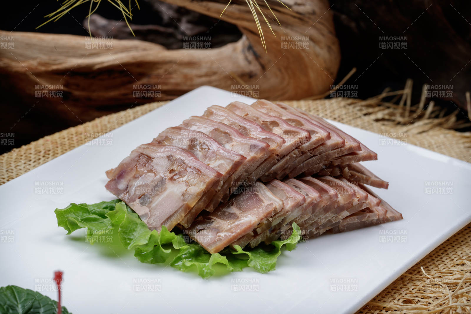 长方形瓷盘装的熏肘花摆放在麻布垫子上图片