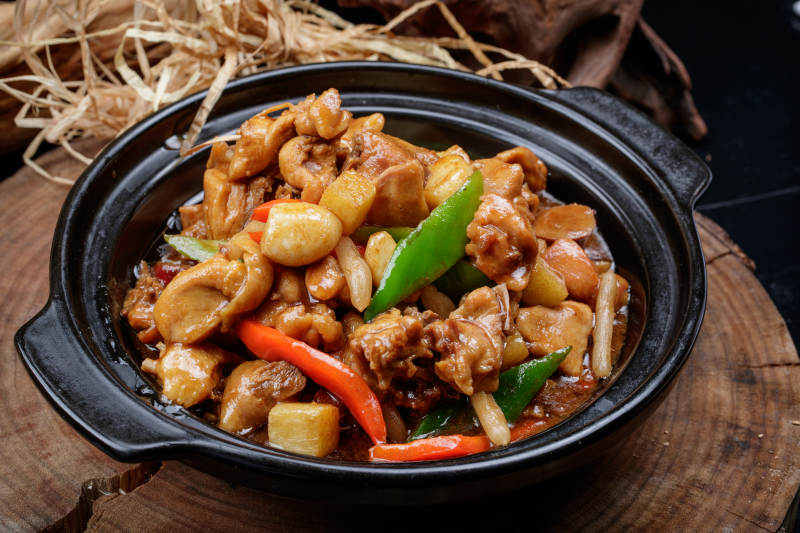 黑色砂锅装的砂锅蒜香鸡摆放在樟木砧板上图片