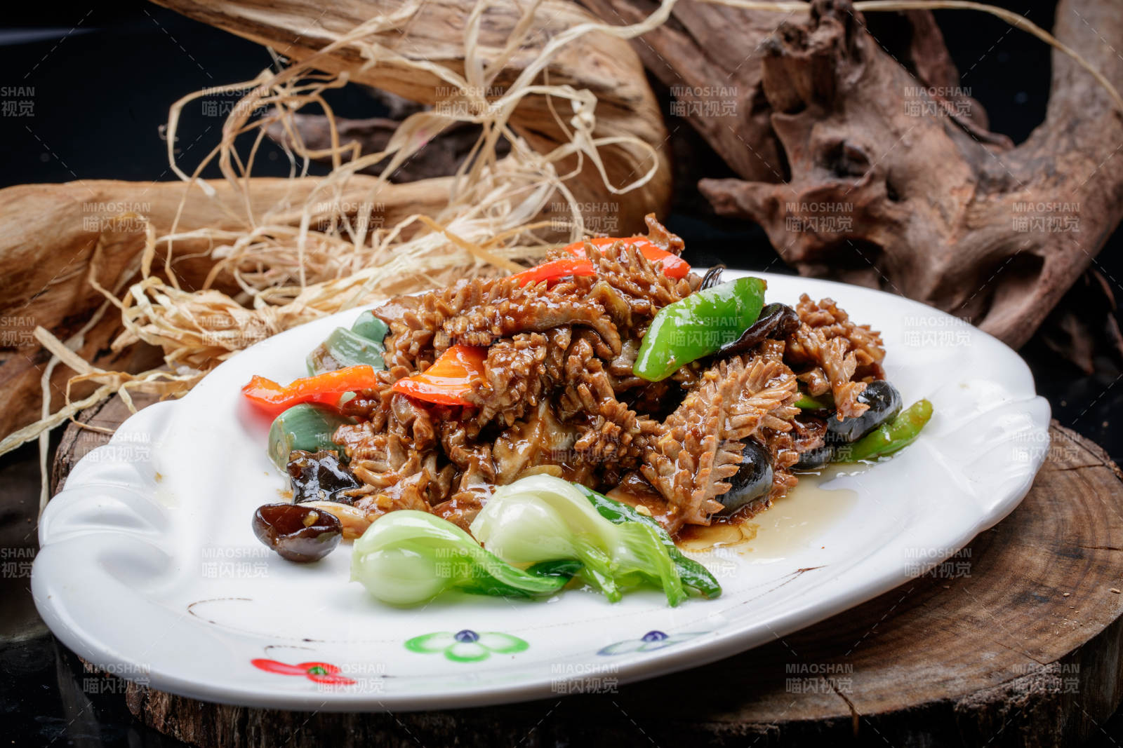 椭圆瓷盘装的腊八蒜炒腰花摆放在樟木砧板上图片