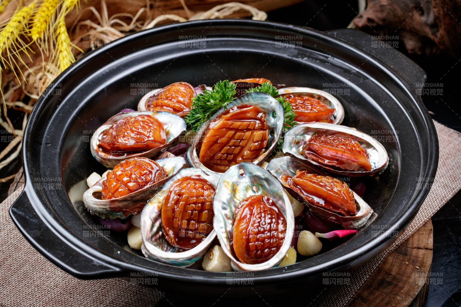 蒜焗砂锅鲜鲍鱼摆放在麻布垫子上图片