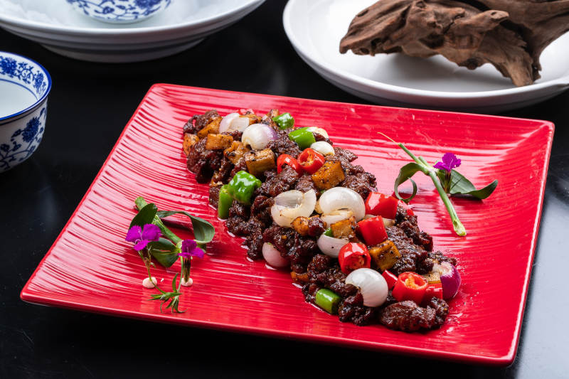 杭椒葱香牛仔粒摆放在黑色背景上图片