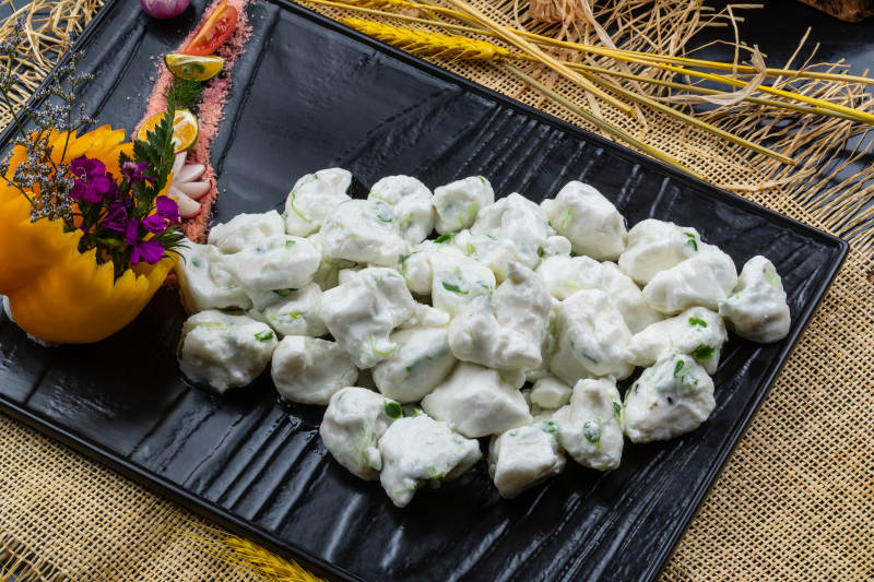 黑色石盘装的香椿芽炒飞龙摆放在麻布垫子上图片