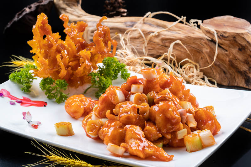 造型奇特的的宫保大虾球摆放在黑色背景上图片