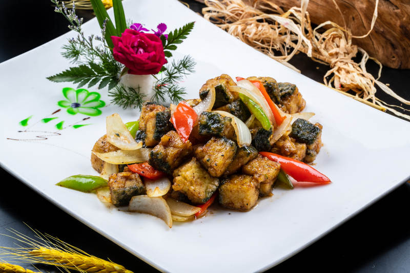 椒麻炸深海鱼块摆放在黑色背景上图片