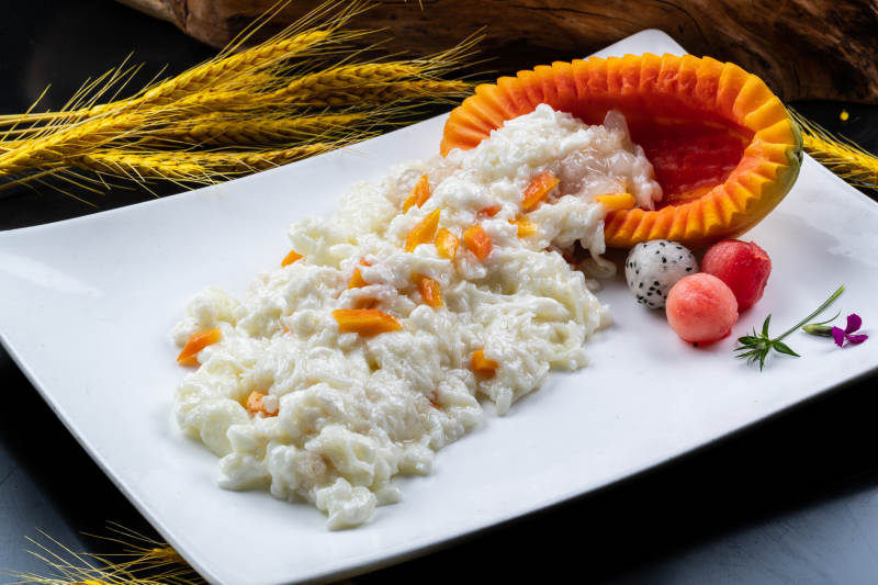 长方形瓷盘装的木瓜芙蓉蛋摆放在黑色背景上图片