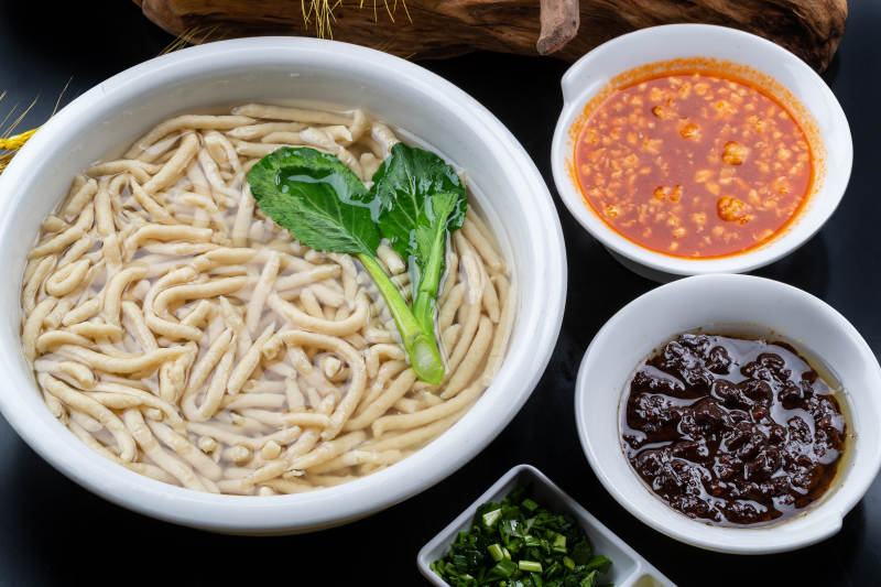 拨鱼西红柿打卤炸酱摆放在黑色背景上图片