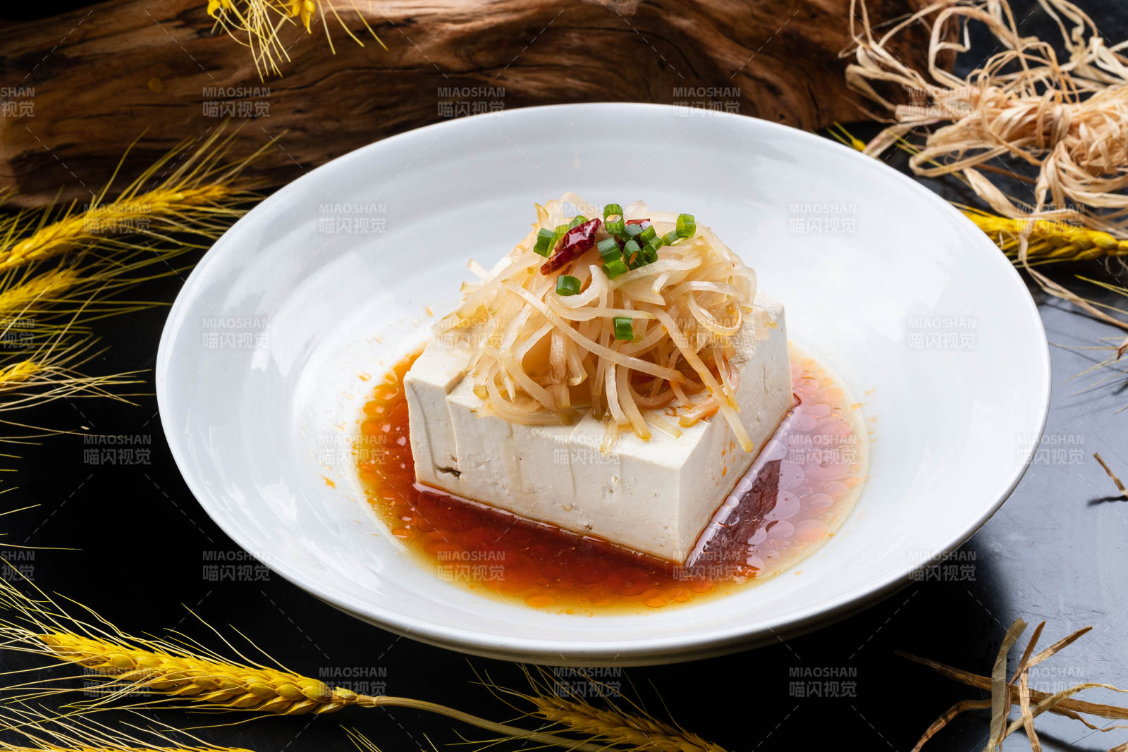 圆形瓷盘装的一品豆腐摆放在黑色背景上图片