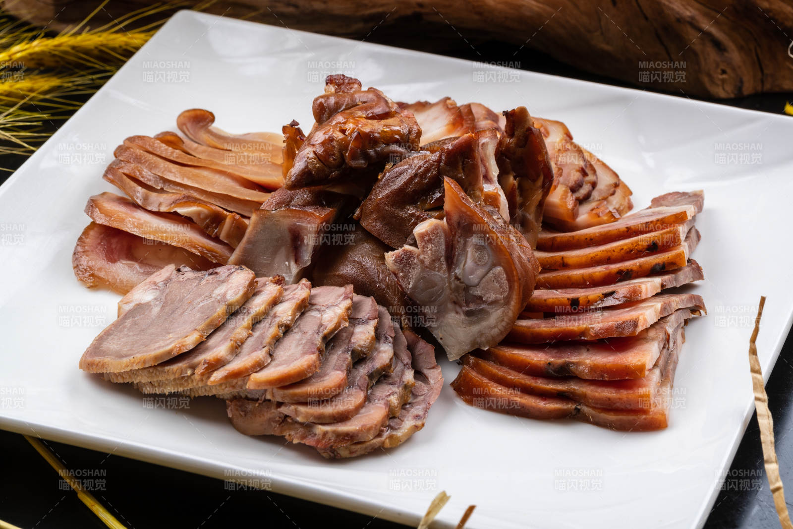 方形瓷盘装的卤肉拼盘摆放在黑色背景上图片