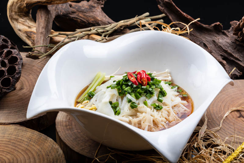 心型瓷盆装的晋味鸡汤凉皮摆放在樟木砧板上图片