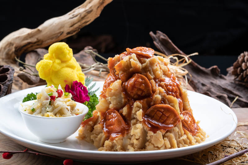 白色圆盘装的土豆焖鲍鱼摆放在樟木砧板上图片