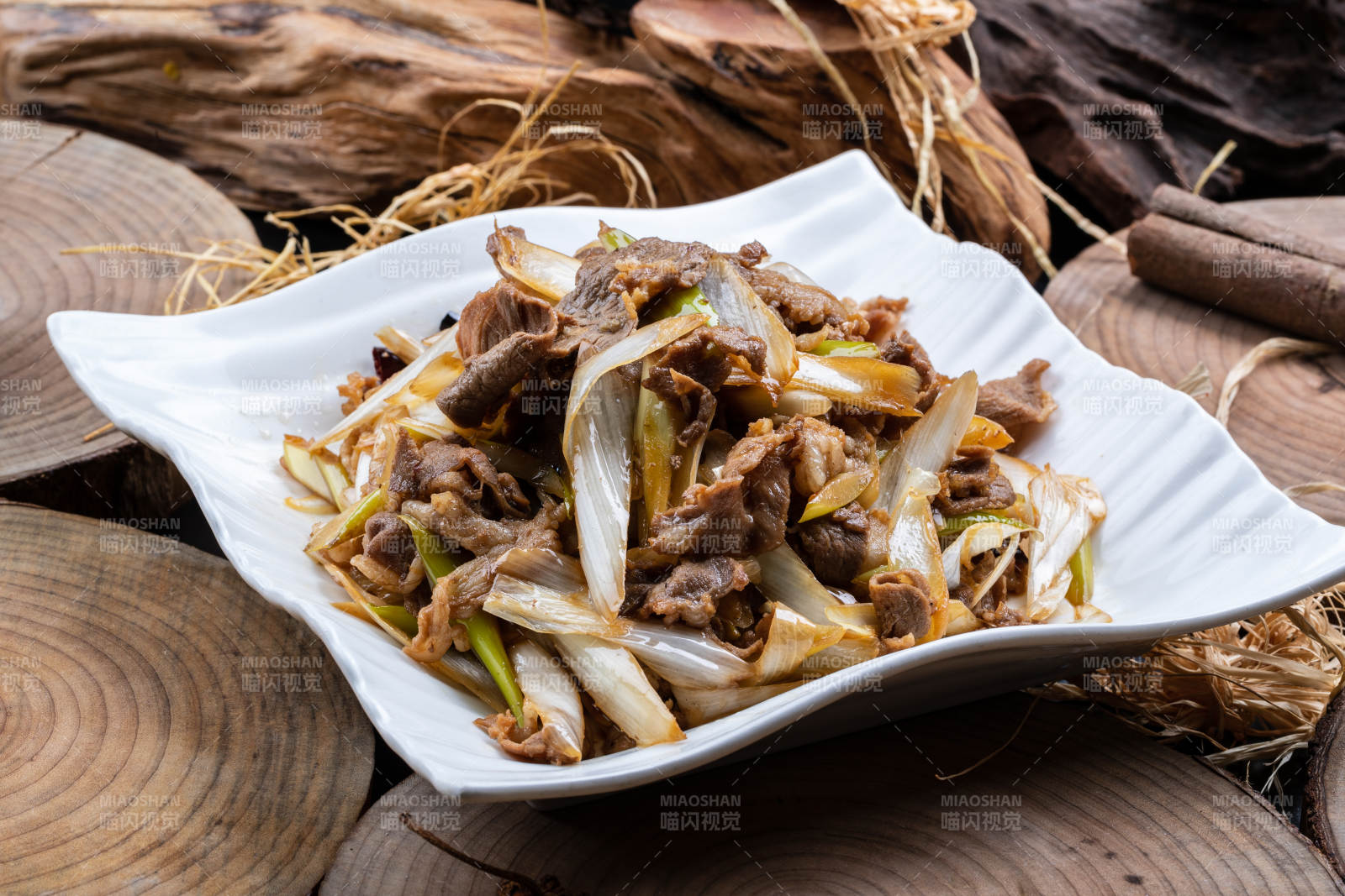 方形花瓷盘装的大葱爆羊肉摆放在樟木砧板上图片