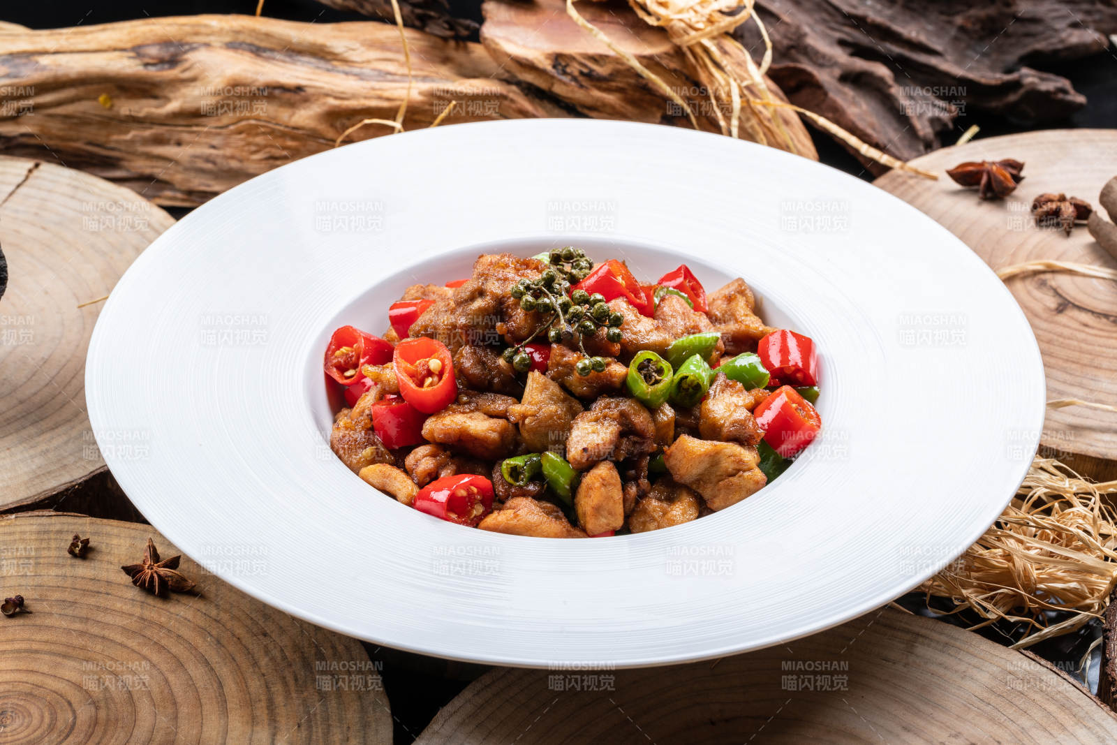 白色圆盘装的麻辣烧公鸡摆放在樟木砧板上图片
