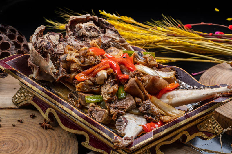 红漆木盘装的水煮蒜泥羊头摆放在樟木砧板上图片