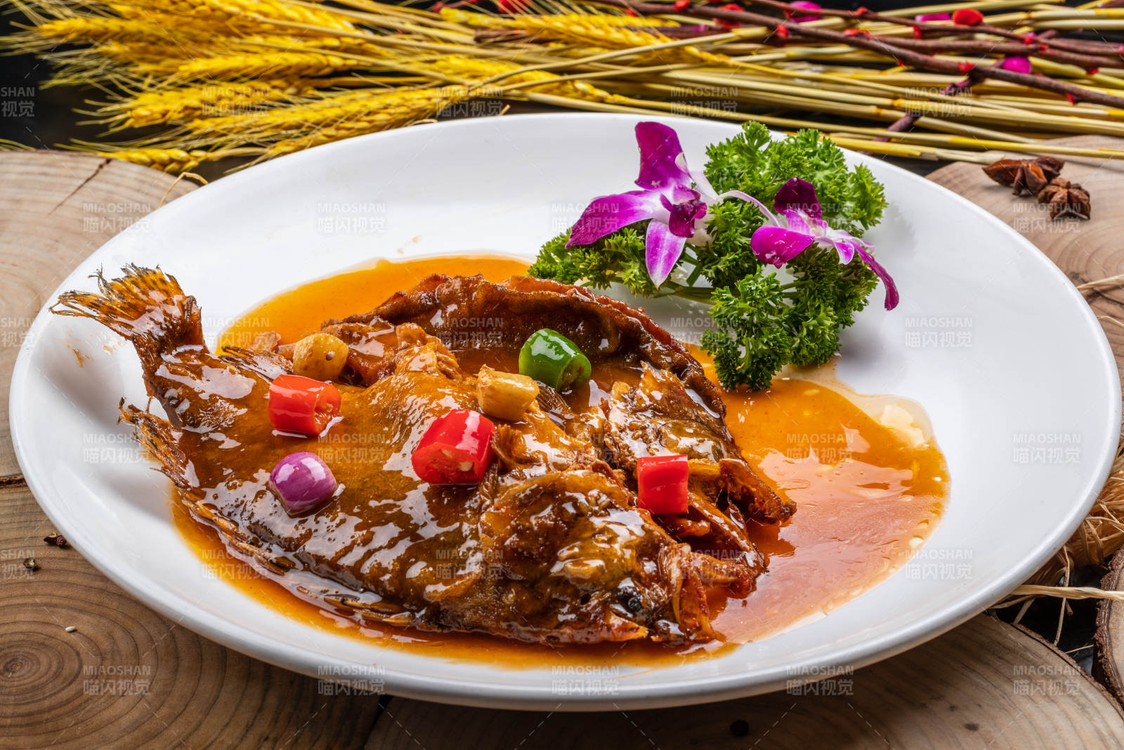 白色圆盘装的红烧罗非鱼摆放在樟木砧板上图片