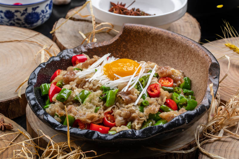 陶盘装的小米辣炒肥牛摆放在樟木砧板上图片