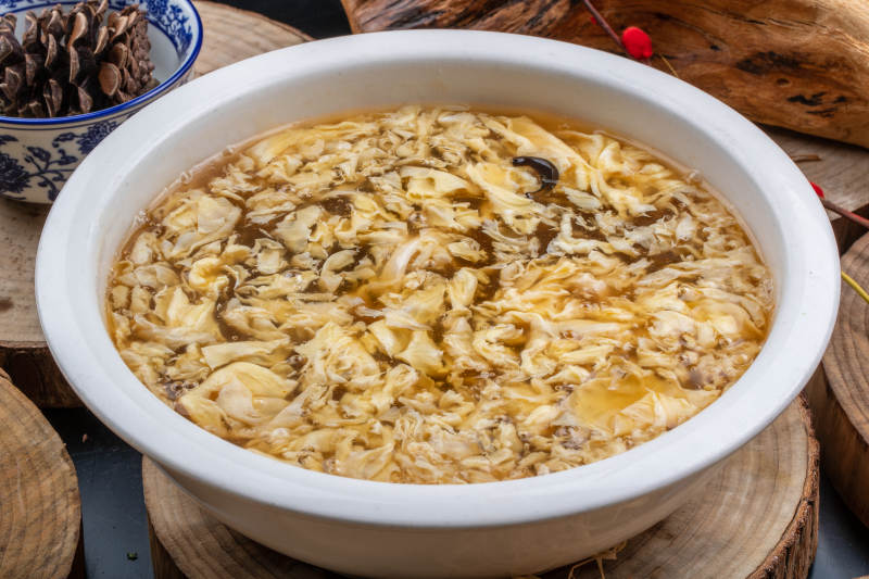 圆形汤盆装的酸辣汤摆放在木板上图片