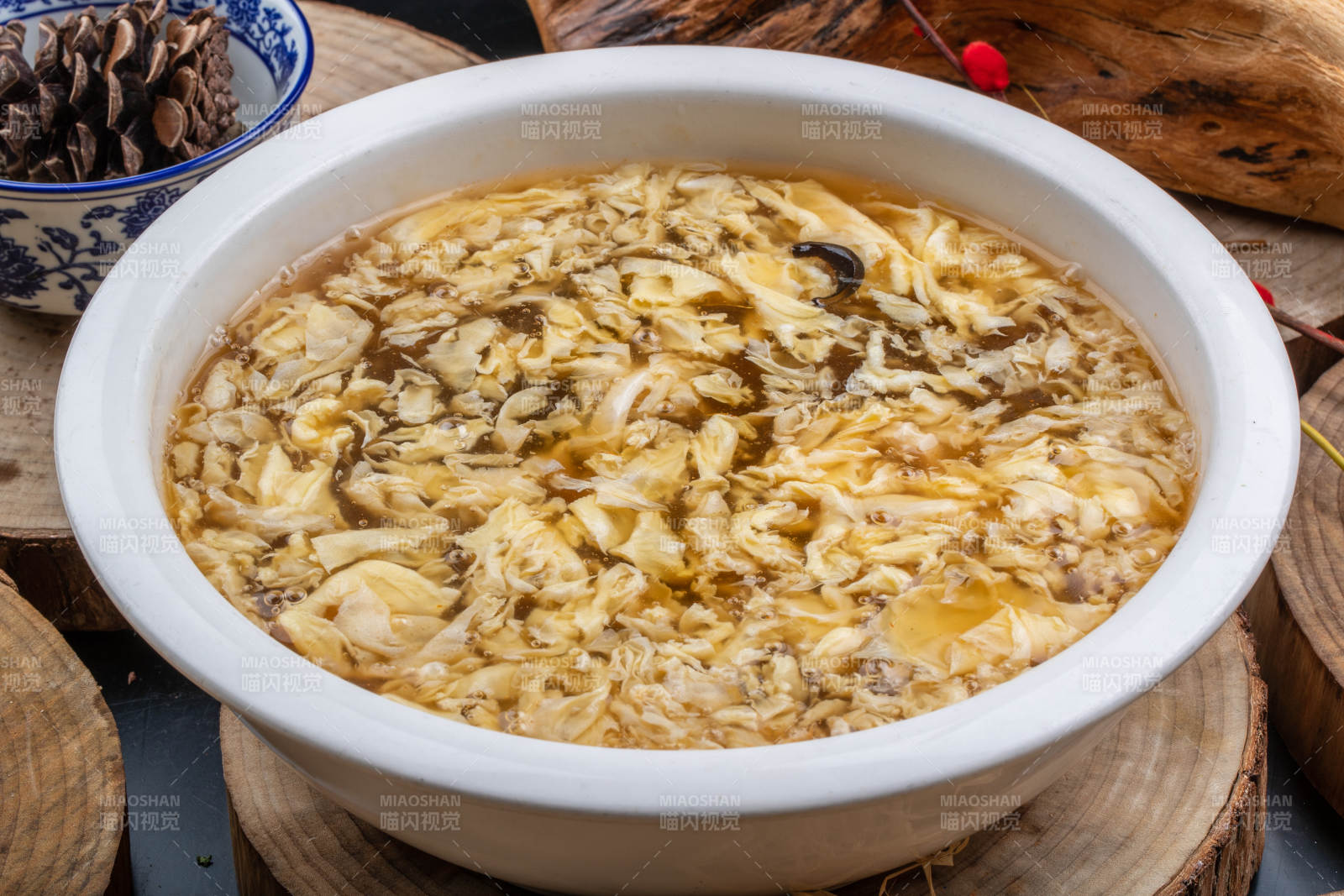 圆形汤盆装的酸辣汤摆放在木板上图片