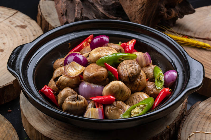 黑色砂锅装的小葱头鲜口蘑米椒煲图片