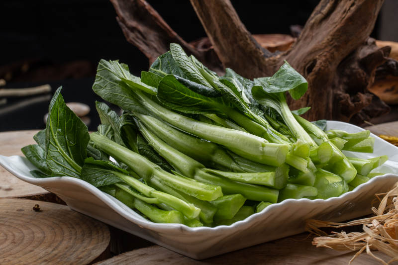 白色瓷盘装的生鲜新鲜菜心图片