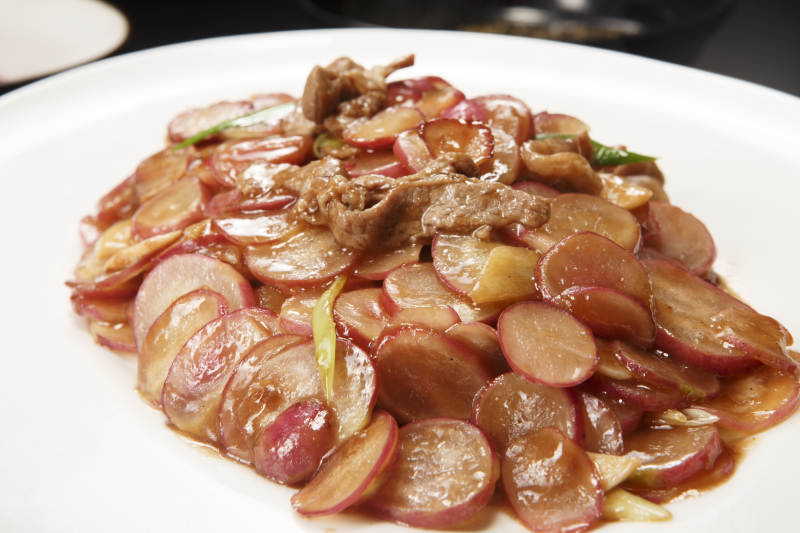 白色瓷盘装的五花肉炒水萝卜图片