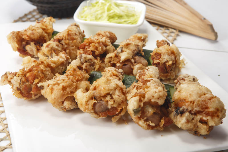 白色瓷盘装的粽叶蒜香鸡翅根图片