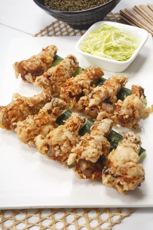 白色瓷盘装的粽叶蒜香鸡翅根图片