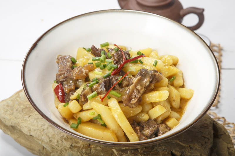 白色瓷碗装的牛腩烧土豆图片