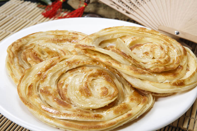 白色圆盘装的葱油饼图片