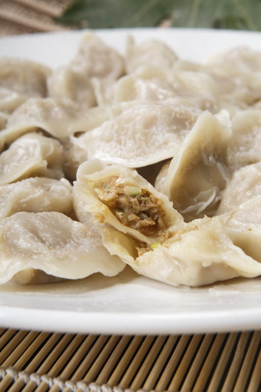 刚出锅的猪肉大葱饺子摆放在白色背景上图片