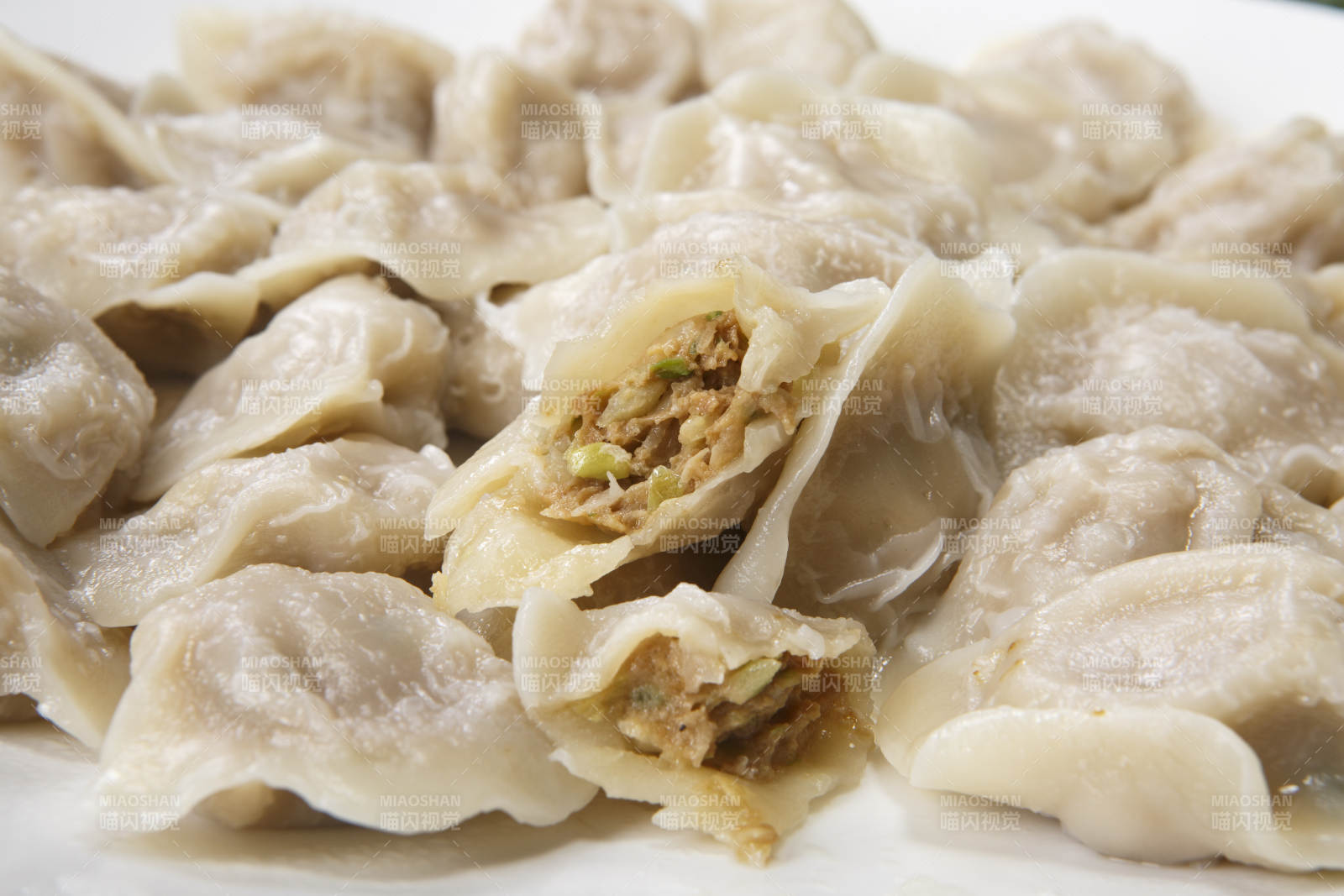 刚出锅的猪肉大葱饺子摆放在白色背景上图片