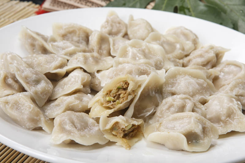 刚出锅的猪肉大葱饺子摆放在白色背景上图片