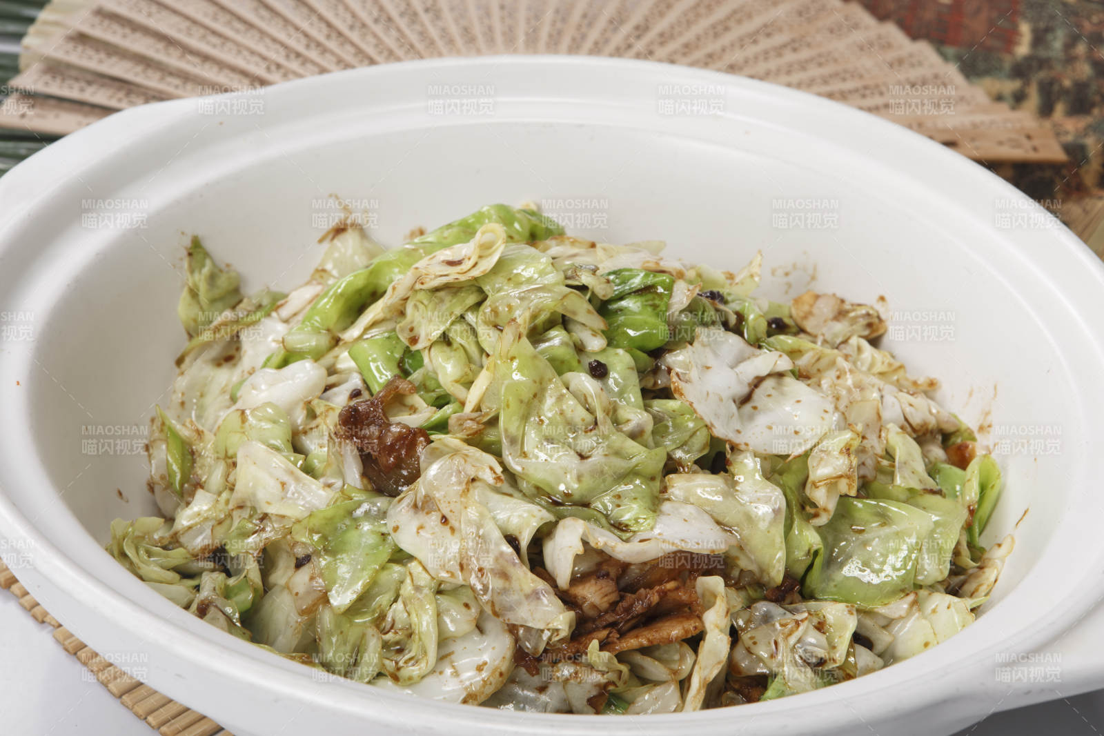 寿司帘上的白色砂锅装的油渣爆包菜图片