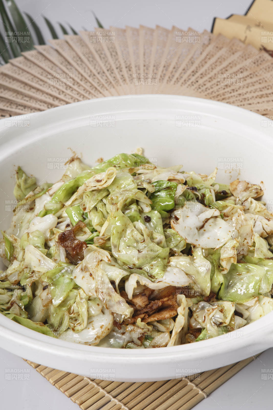 寿司帘上的白色砂锅装的油渣爆包菜图片