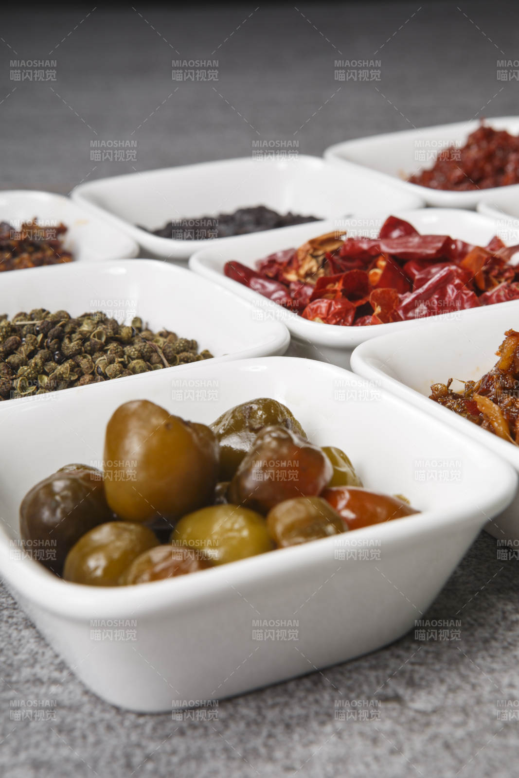 白色方磁盘装的调料摆放在灰色石板图片