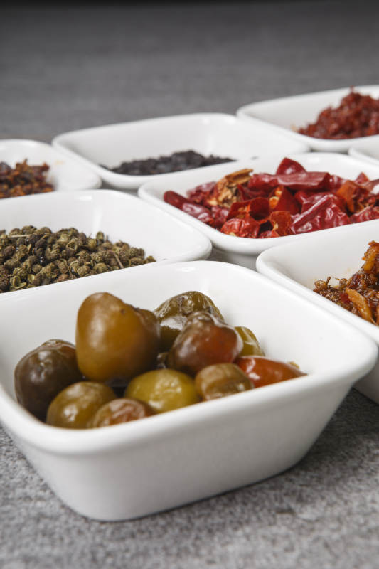 白色方磁盘装的调料摆放在灰色石板图片