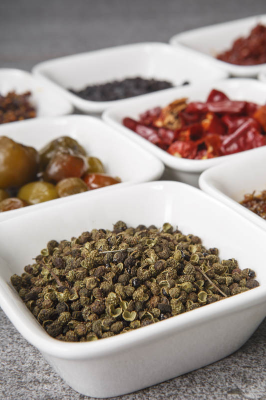 白色方磁盘装的调料摆放在灰色石板图片