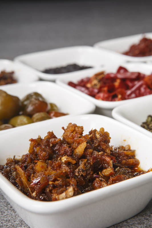 白色方磁盘装的调料摆放在灰色石板图片