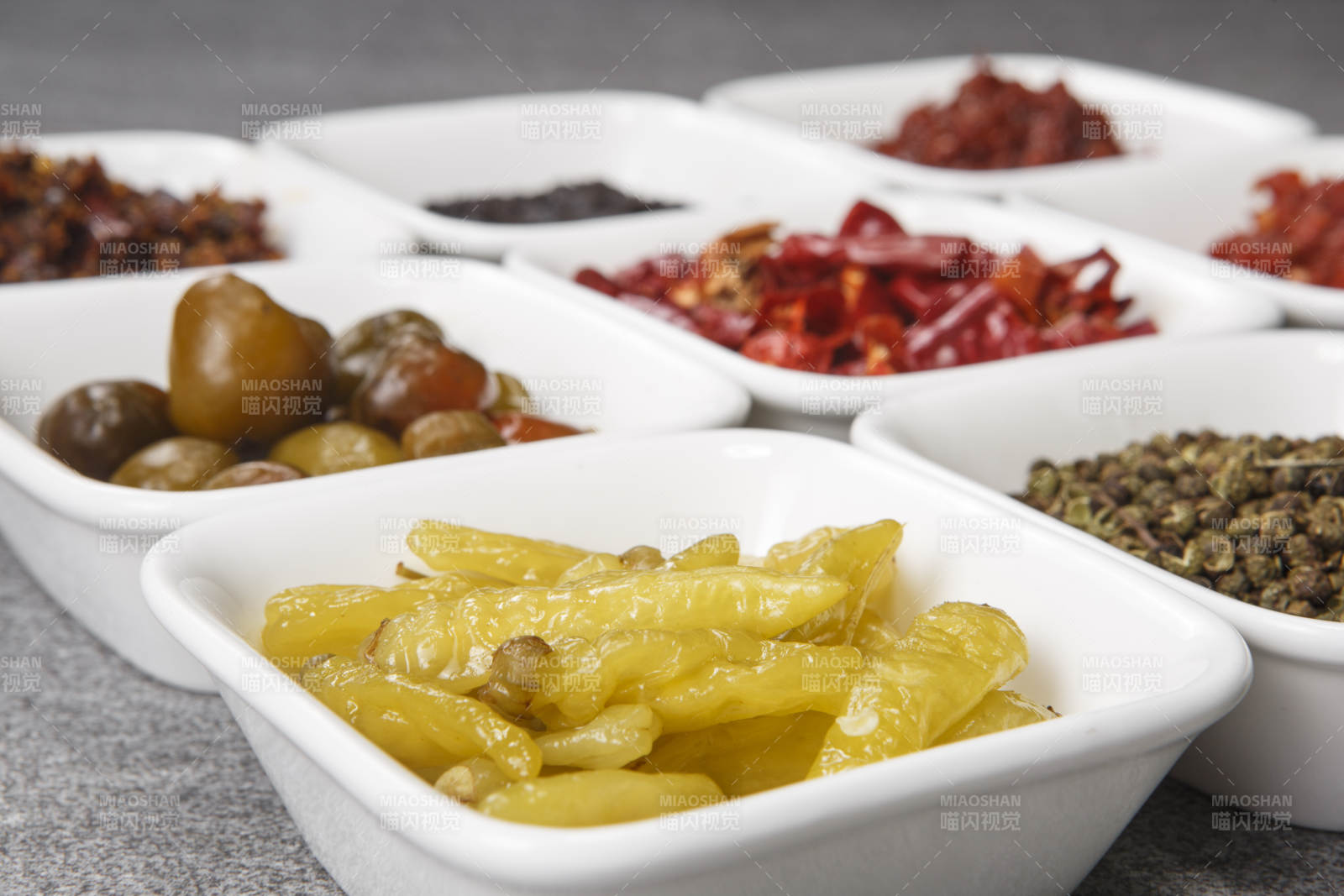 白色方磁盘装的调料摆放在灰色石板图片