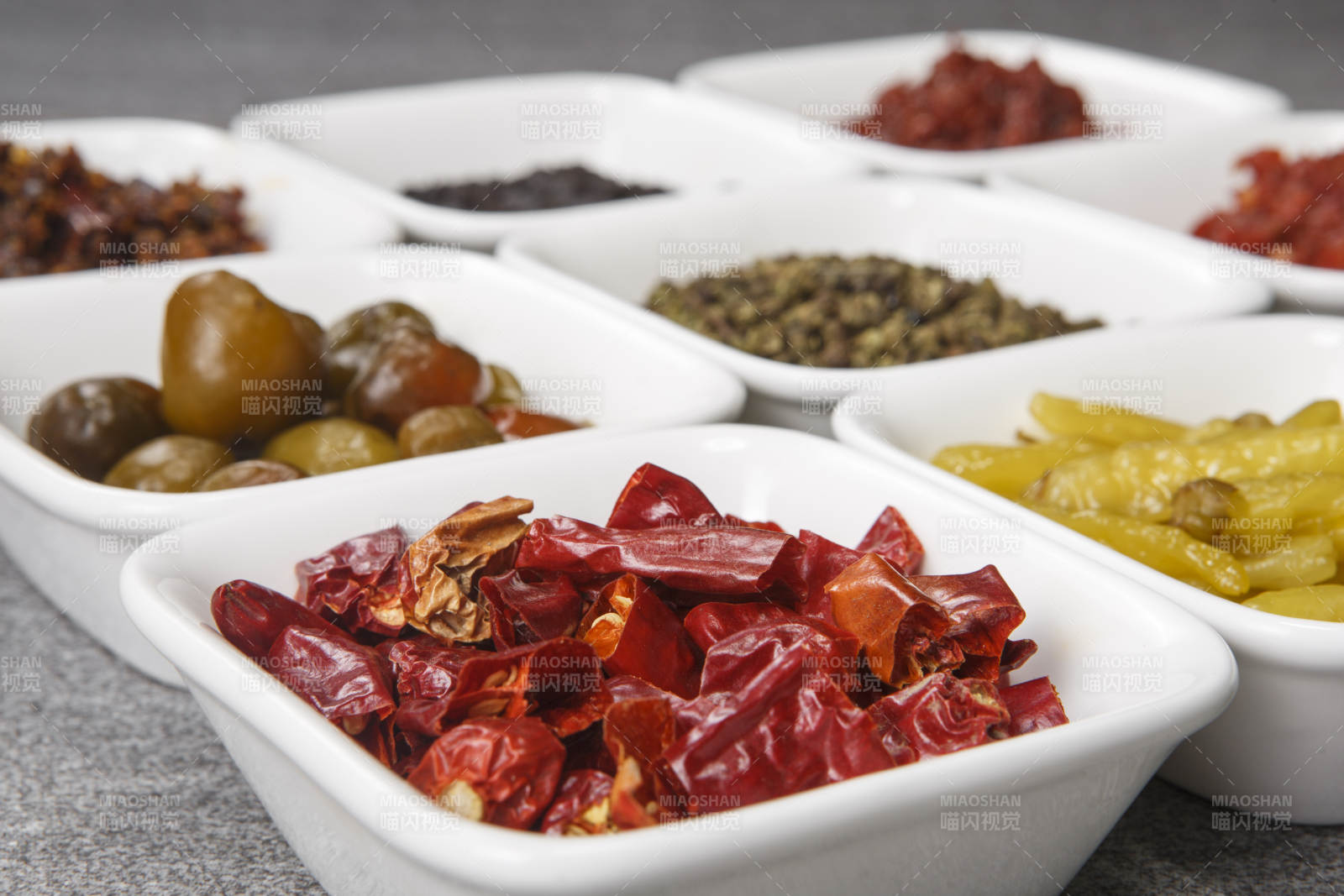 白色方磁盘装的调料摆放在灰色石板图片