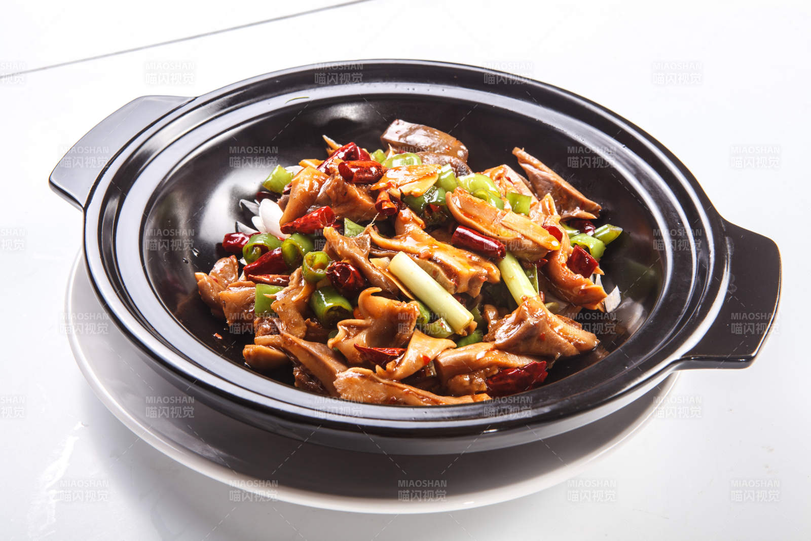 白色背景下黑色砂锅米椒辣猪肚图片