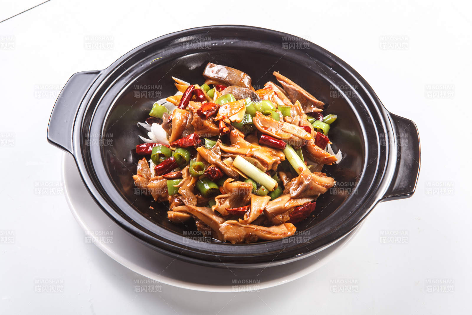 白色背景下黑色砂锅米椒辣猪肚图片