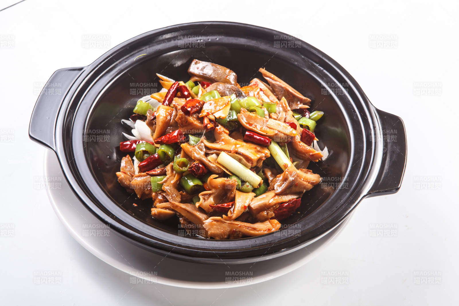 白色背景下黑色砂锅米椒辣猪肚图片