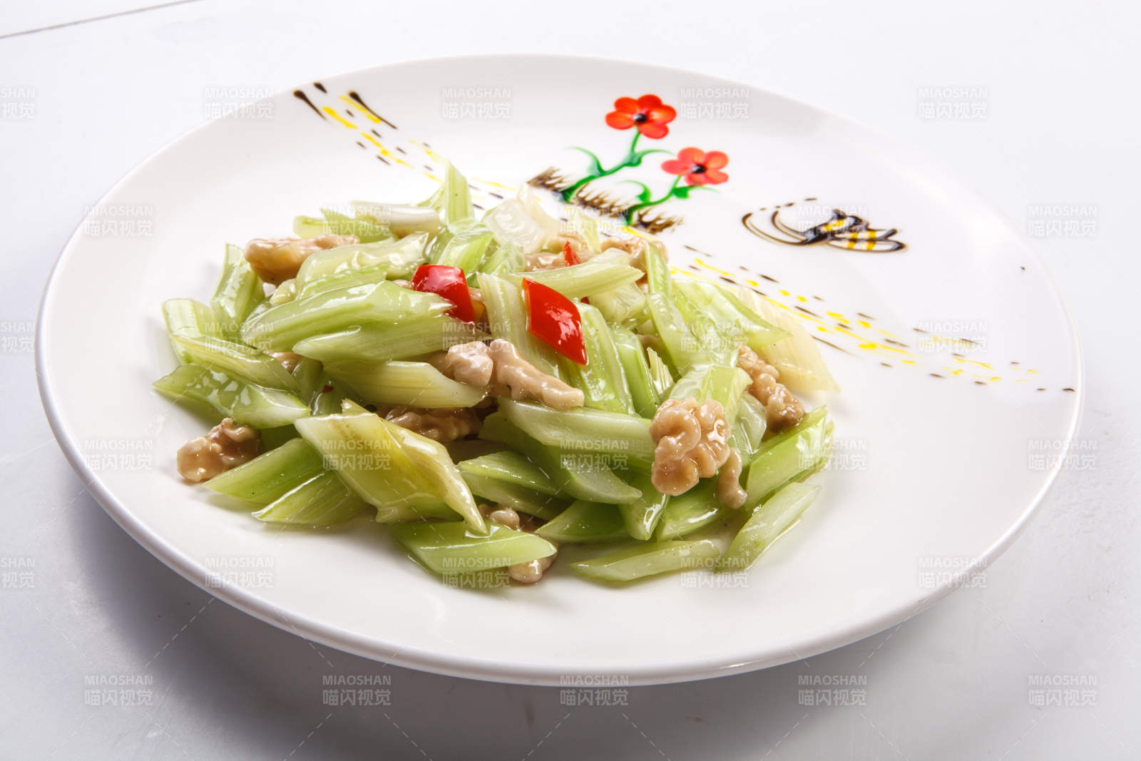 白色瓷盘装的西芹炒桃仁图片