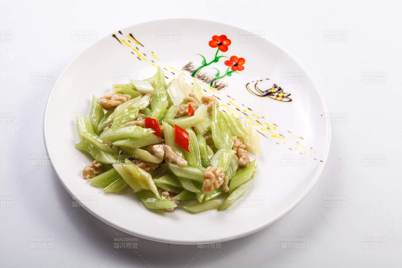 白色瓷盘装的西芹炒桃仁图片