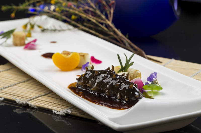 白色瓷盘装的葱烧海参图片